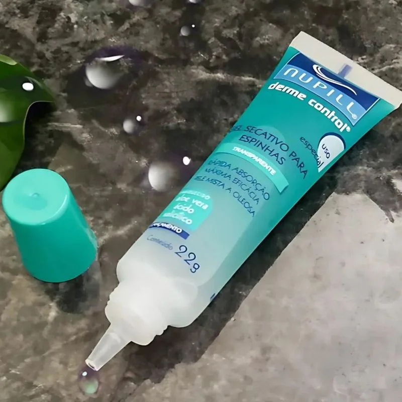 Gel Secativo de Espinhas Nupill Derme Control 22g sobre superfície de mármore com folha verde