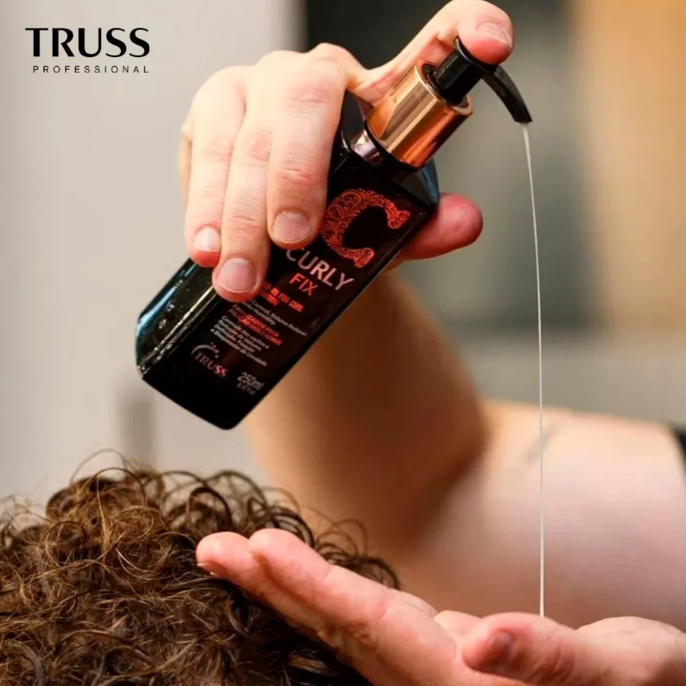 Aplicação do Leave-in Curly Fix Truss Professional na palma da mão com cabelo cacheado ao fundo
