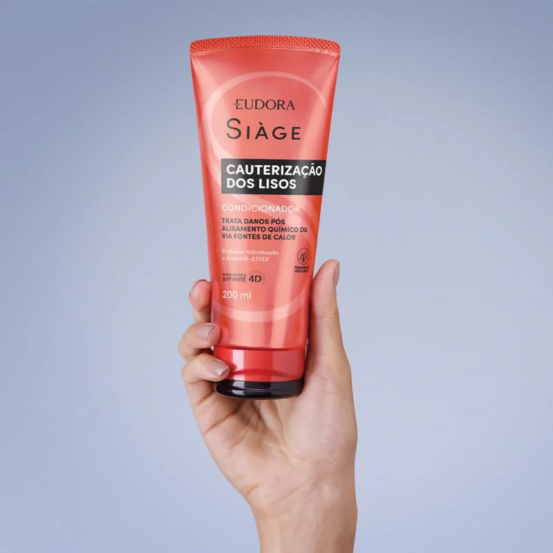 Mão segurando o condicionador Siáge Cauterização Dos Lisos 200ml