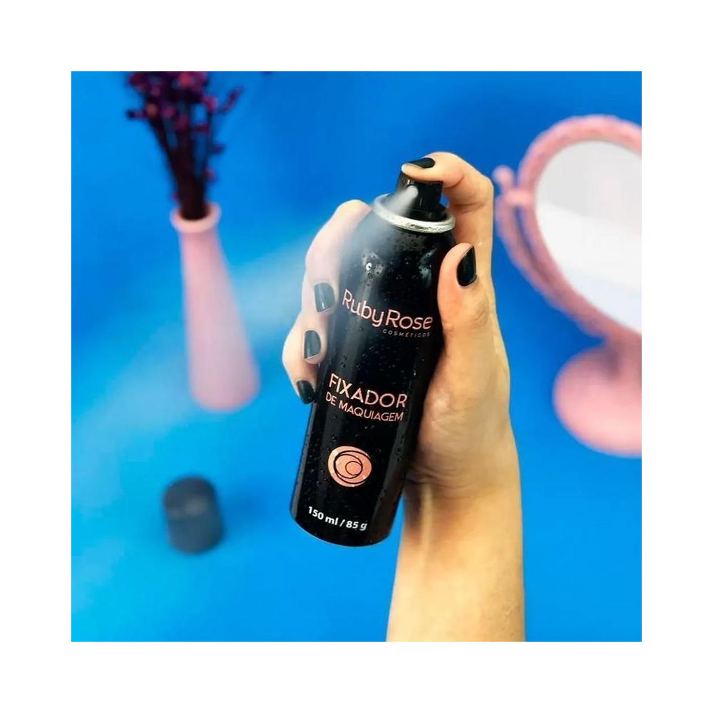 Mão acionando o Spray Fixador Ruby Rose com névoa visível